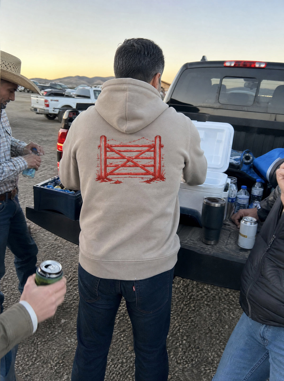 Man in a Mushroom El Corral Hoodie, back view, digging in a cooler at a rodeo parking lot tailgate